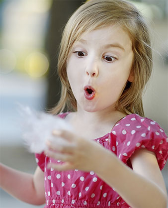 garota admirada comendo algodão doce colorido