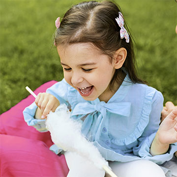 criança feliz comendo algodão doce colorido